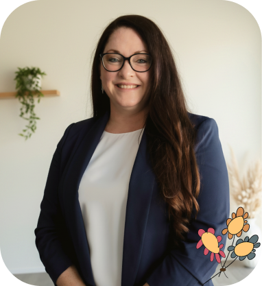 Woman with long brown hair and glasses, wearing a navy blazer and white top, standing indoors with a plant and floral graphic in the background.