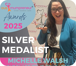A woman holding a trophy stands in front of an “AusMumpreneur Awards 2025” banner, with text reading “Silver Medallist Michelle Walsh.”.