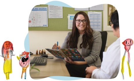 A woman in business attire sits at a desk, holding a colourful folder and smiling at another person during a meeting; children’s drawings decorate the image border.
